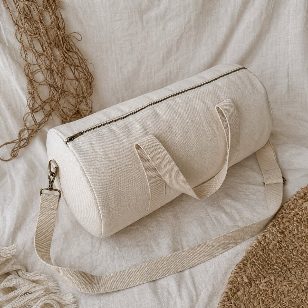 A cylindrical canvas duffel bag with a long top zip